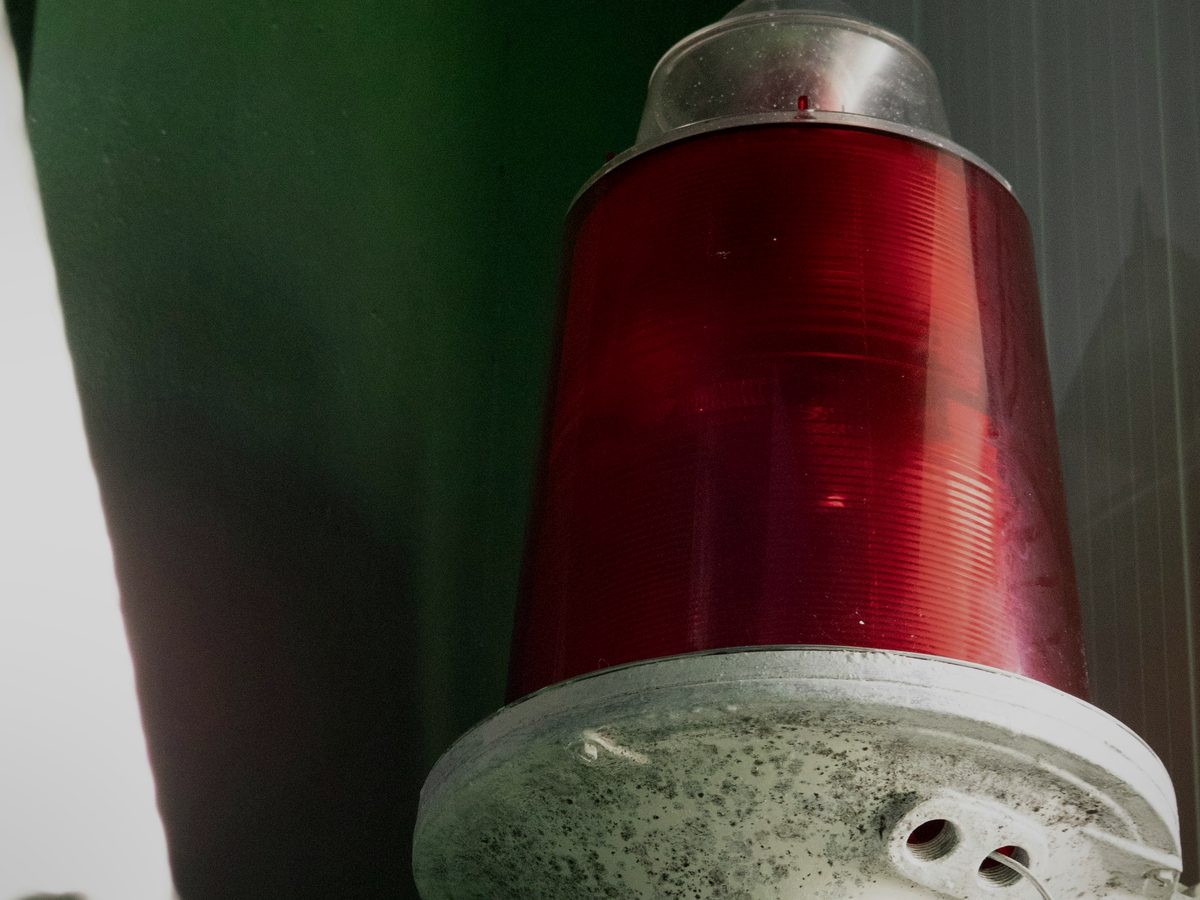 A red warning light on a machine, not yet lit.